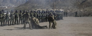members of Customs and Border Protection dressed in camouflage drag away a fellow agent pretending to be an injured protestor during training exercise